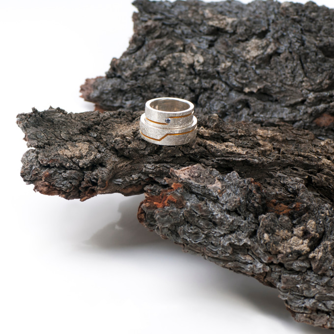 Ein vergoldetes vertieftes Band wechselt die Position auf diesen silbernen Ringen von Edel und Stein Esslingen
